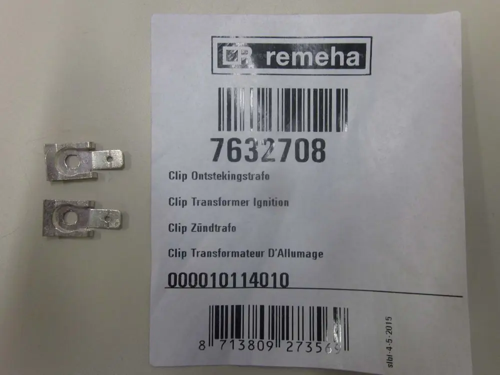 Zwei metallische Clips neben einem Etikett von Remeha mit Artikelnummer und mehrsprachiger Beschreibung für Zündtrafo-Teile.